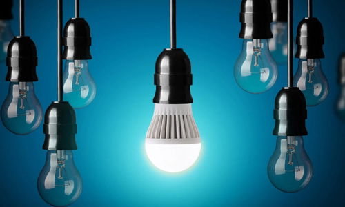 Hanging light bulbs against a blue background with the middle light bulb lit up