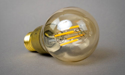 LED Filament Bulb On Its Side, not illuminated with a gold coloured base