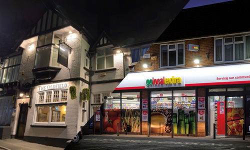 Warm white sign lighting on a tudor style pub and cool white sign lighting on a modern convenience store