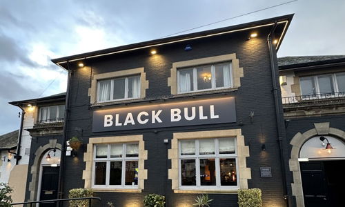 Black Bull Sizzling Pub with Warm White Exterior Floodlights and Sign Lighting switched on during the day time